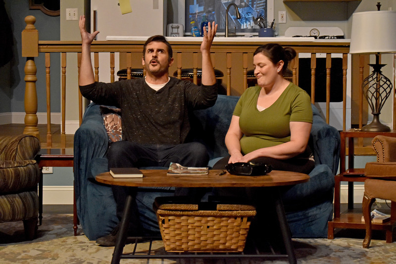 On the couch, he throws his arms up beside his friend.