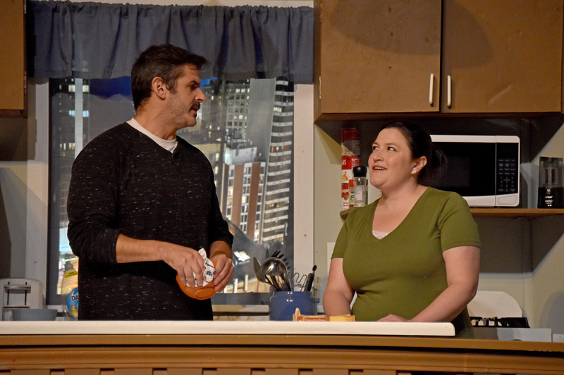 In the kitchen, he holds a bowl as his friend looks on, smiling.