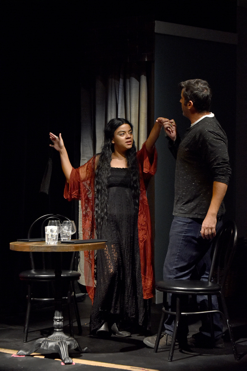 A date in a red robe dances beside the table.