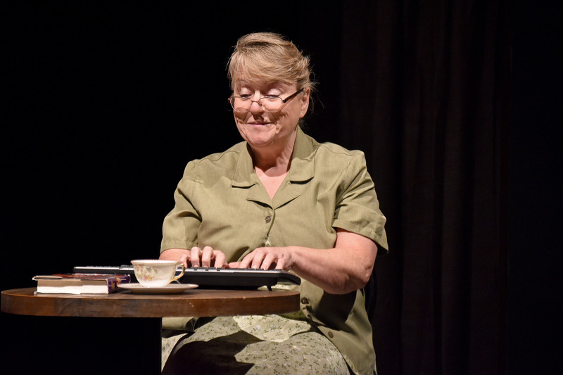At her keyboard, she smiles at the screen.