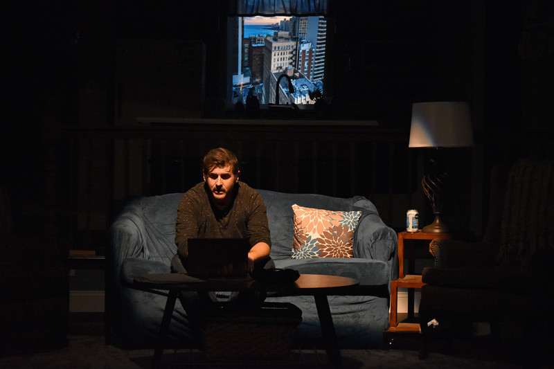 Alone on the couch in the dark, lit by his laptop.