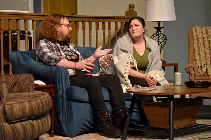 On the couch, his roommate makes a point; she gives him side-eye.